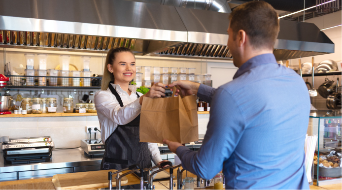 Women handing bag to man in restaurant